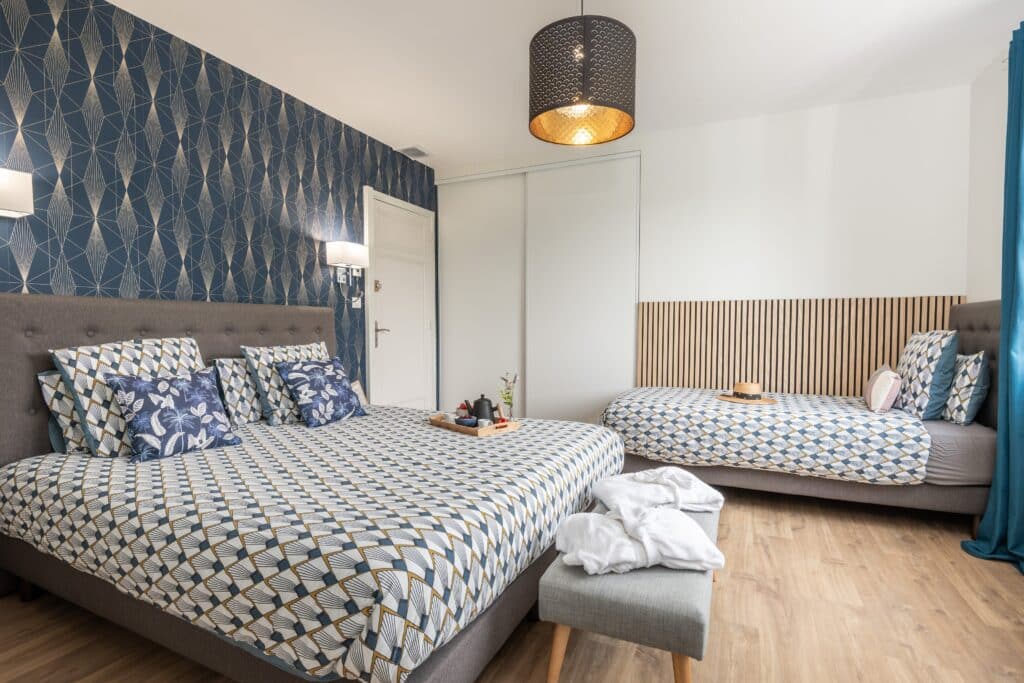 Chambre moderne avec deux lits et décoration géométrique.