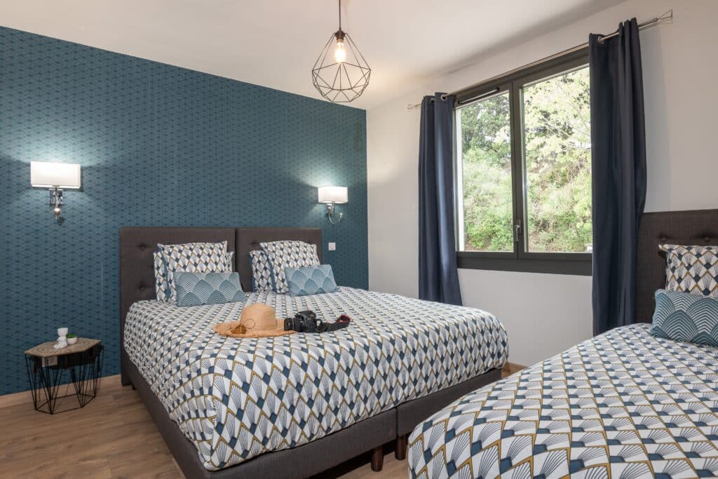 Chambre double avec motif géométrique et vue extérieure.