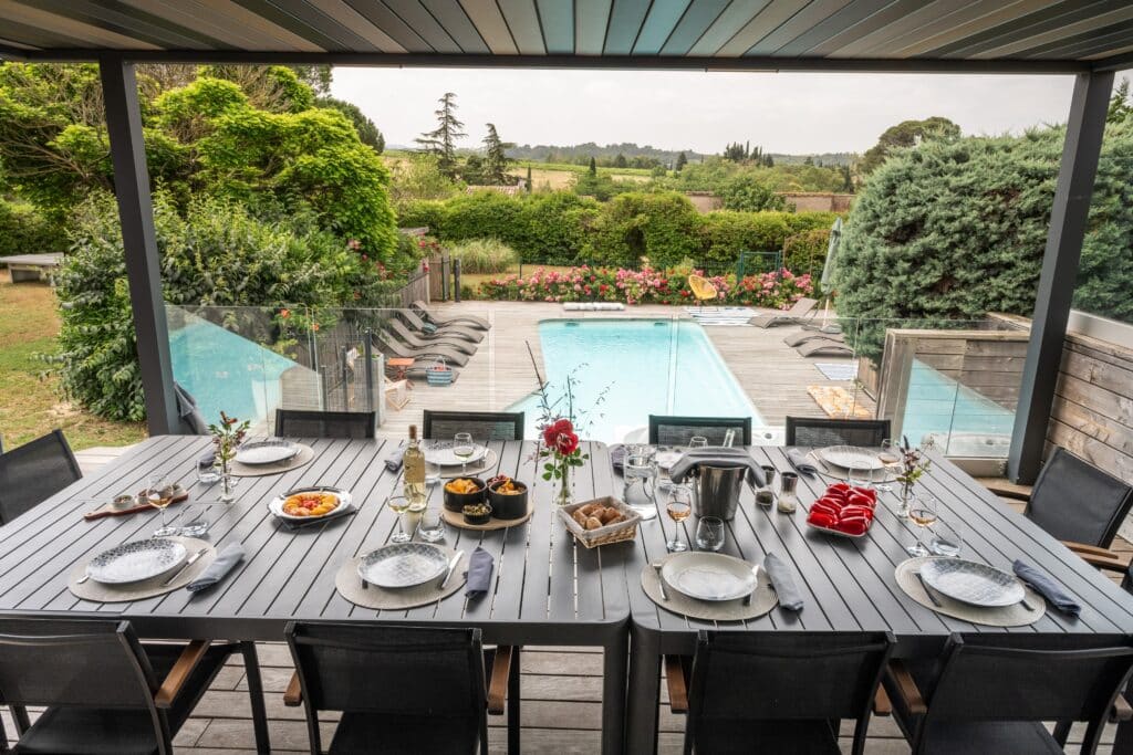 Terrasse avec piscine et table dressée pour dîner.