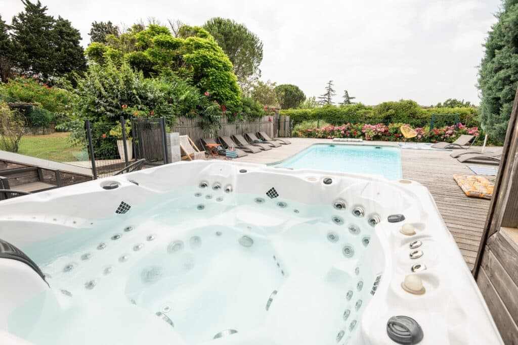 Jacuzzi et piscine dans jardin verdoyant.