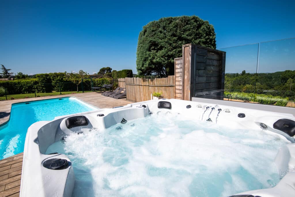 Jacuzzi extérieur près d'une piscine et jardin