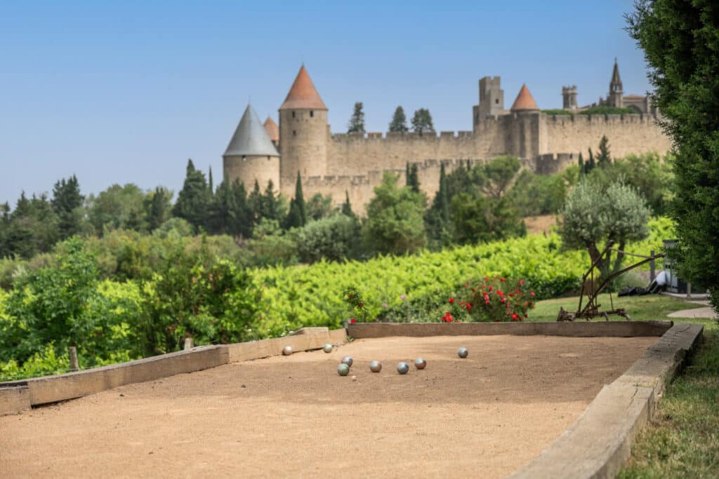 Terrain de pétanque devant château médiéval en été.