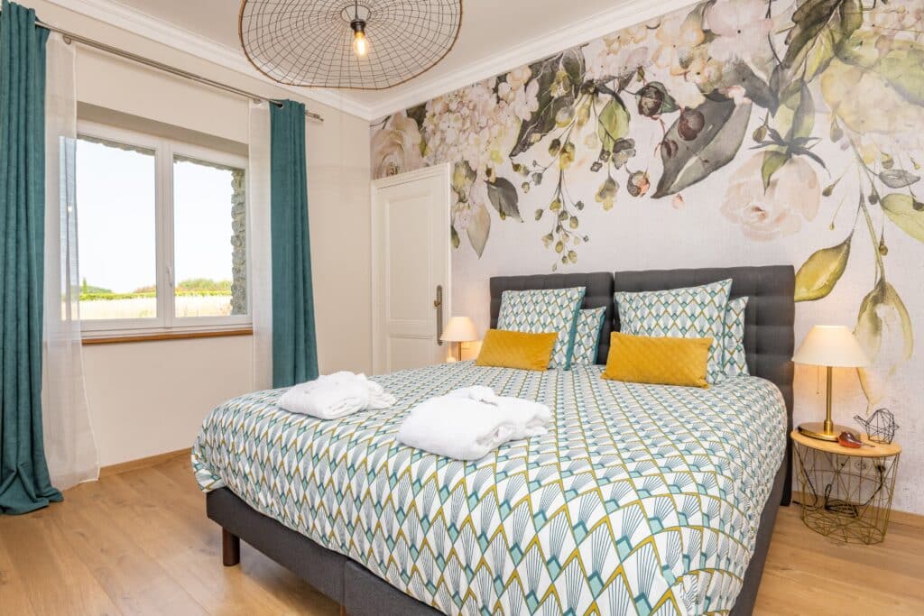 Chambre lumineuse avec lit double et déco florale.