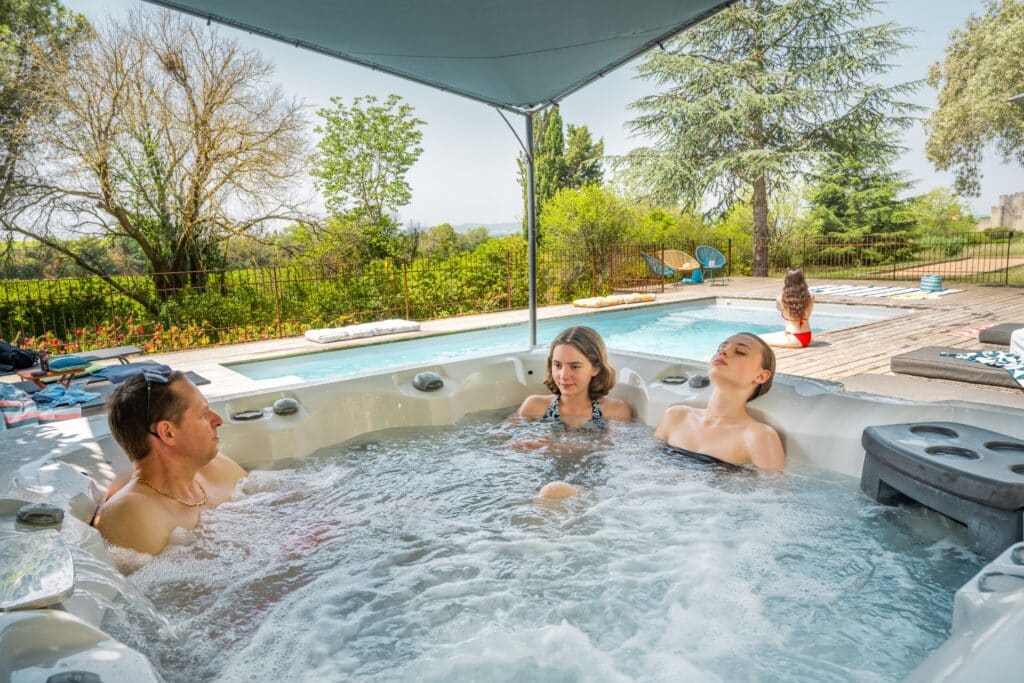 Personnes relaxant dans un jacuzzi près d'une piscine.