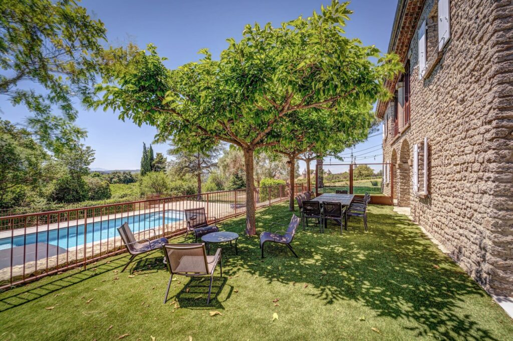 Jardin avec piscine et mobilier extérieur ombragé.