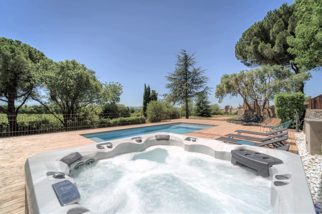 Jardin avec jacuzzi et piscine entourés d'arbres.