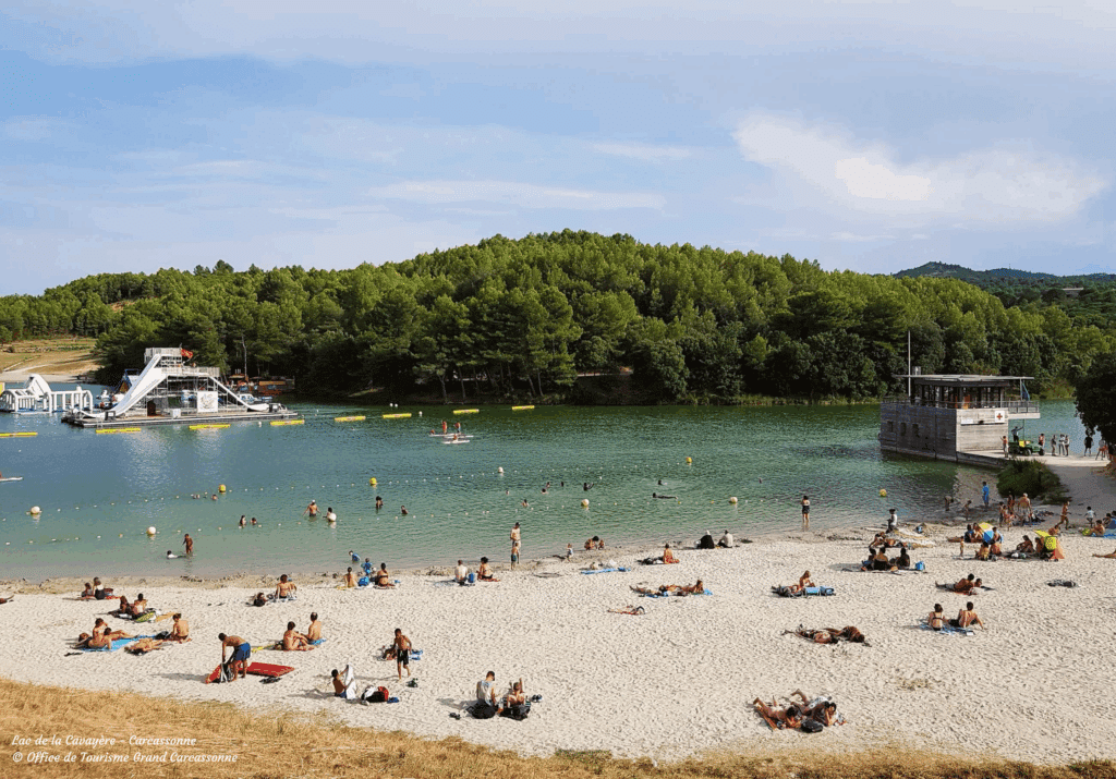 Plage du lac avec baigneurs et toboggan aquatique.
