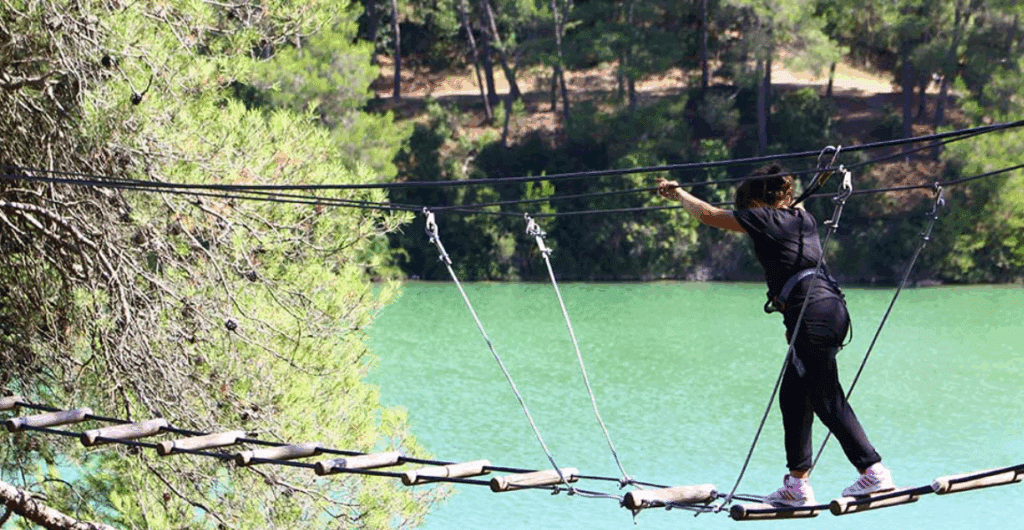 Aventure en tyrolienne au-dessus de l'eau, forêt autour.