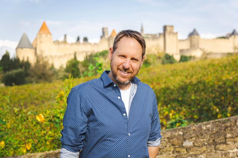 Homme devant château médiéval ensoleillé.