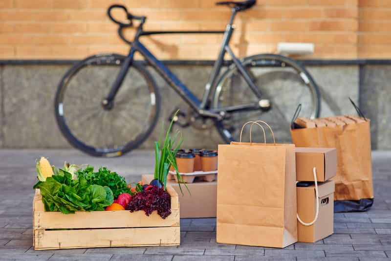 Livraison de courses à vélo, légumes et sacs papier.