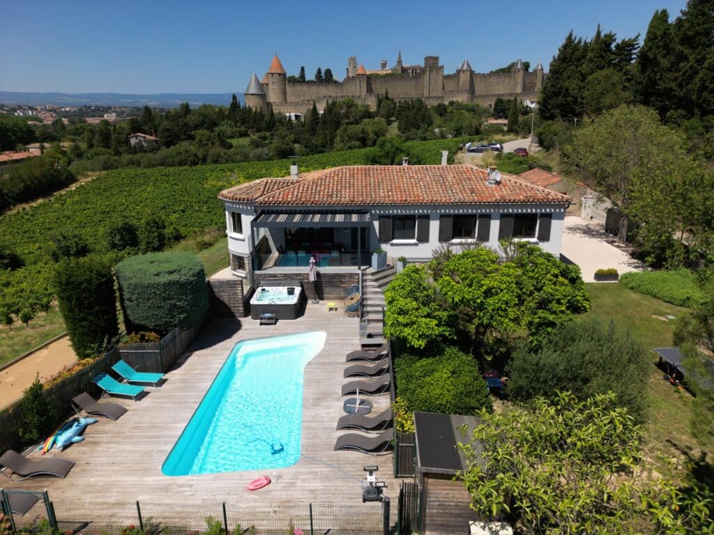 Maison avec jardin, piscine et château médiéval.