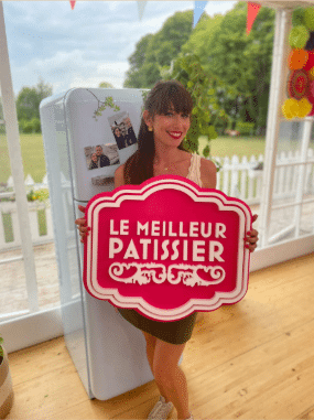 Femme tenant un panneau Le Meilleur Pâtissier