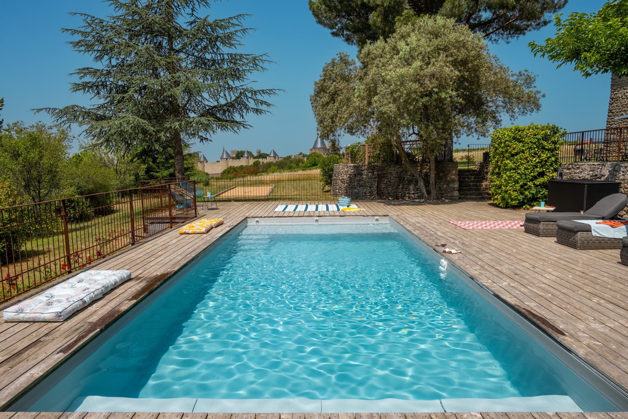 Piscine extérieure avec terrasse en bois et arbres.