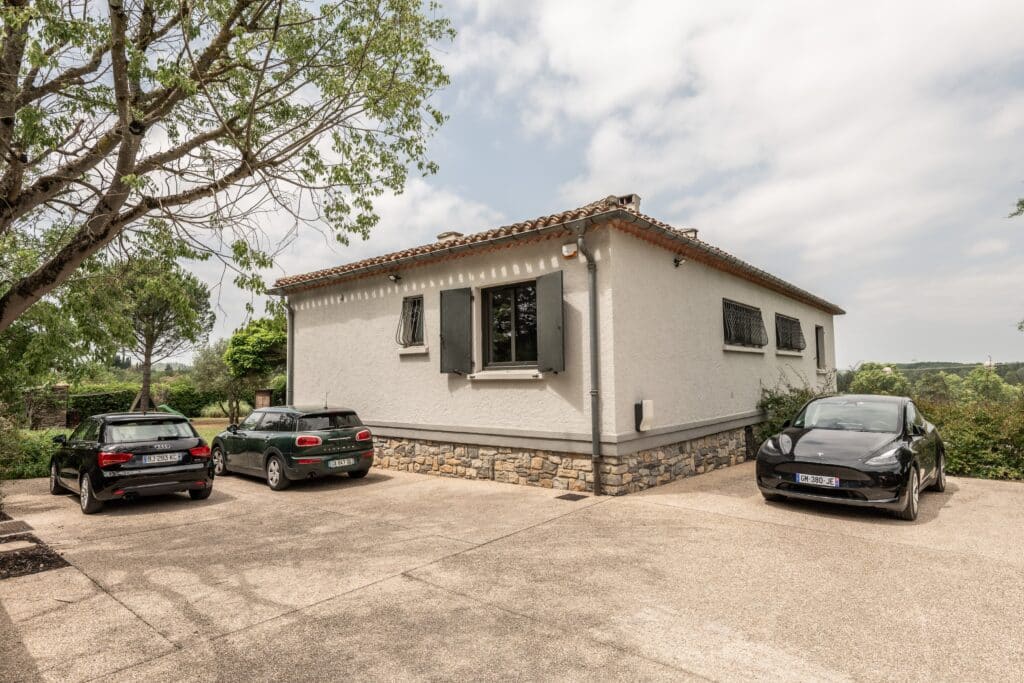 Maison avec trois voitures garées devant.