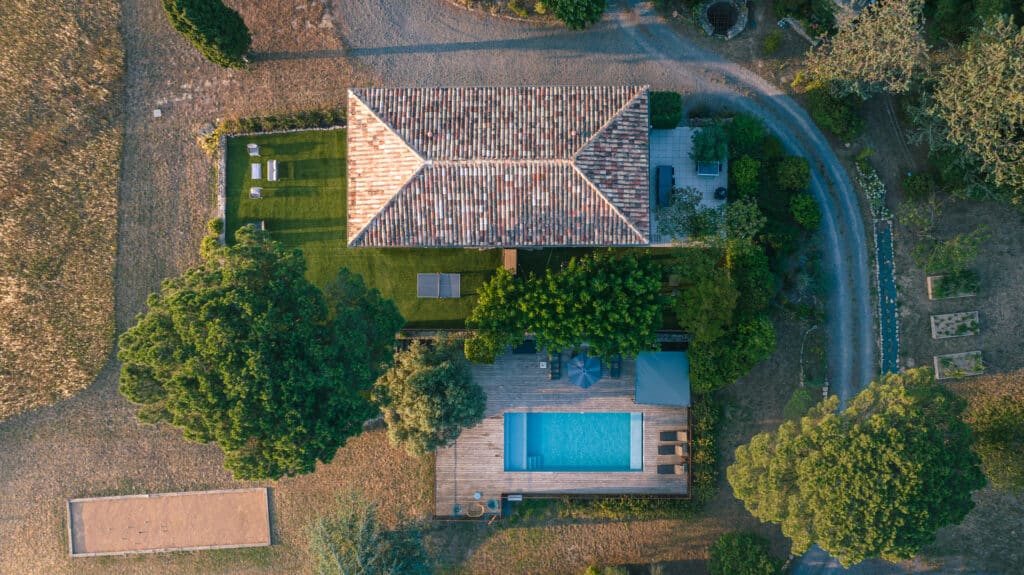 Vue aérienne d'une maison avec piscine et jardin.