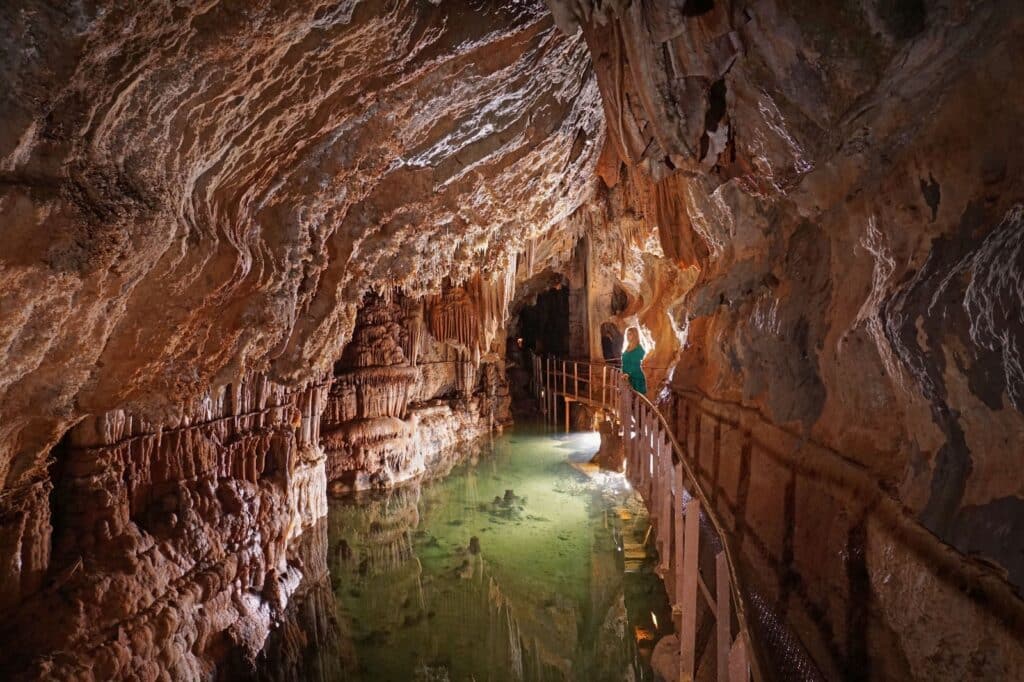 Personne dans une grotte souterraine avec eau turquoise.