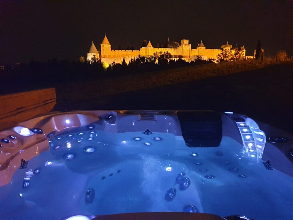 Spa nocturne avec château illuminé en arrière-plan.