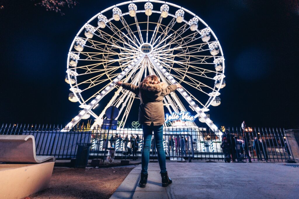 Grande roue illuminée la nuit avec une personne.