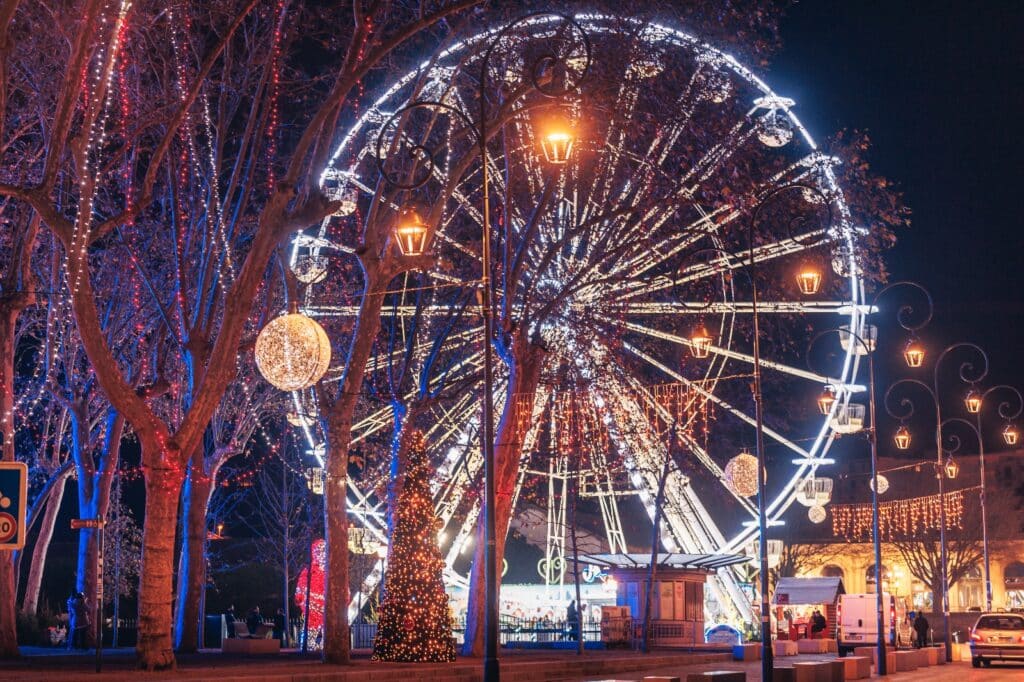 Grande roue illuminée la nuit avec décorations.
