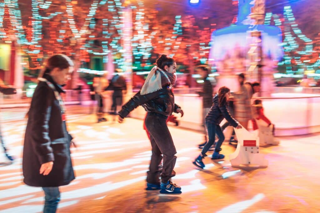 Personnes patinant à glace entourées de lumières colorées.