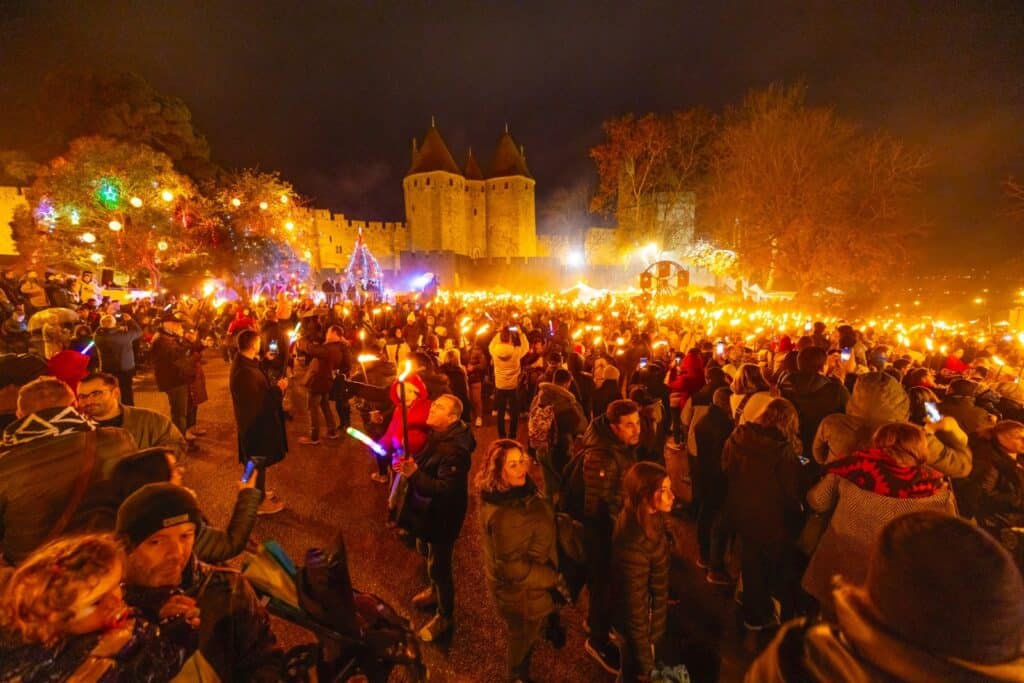 Foule avec flambeaux devant château illuminé