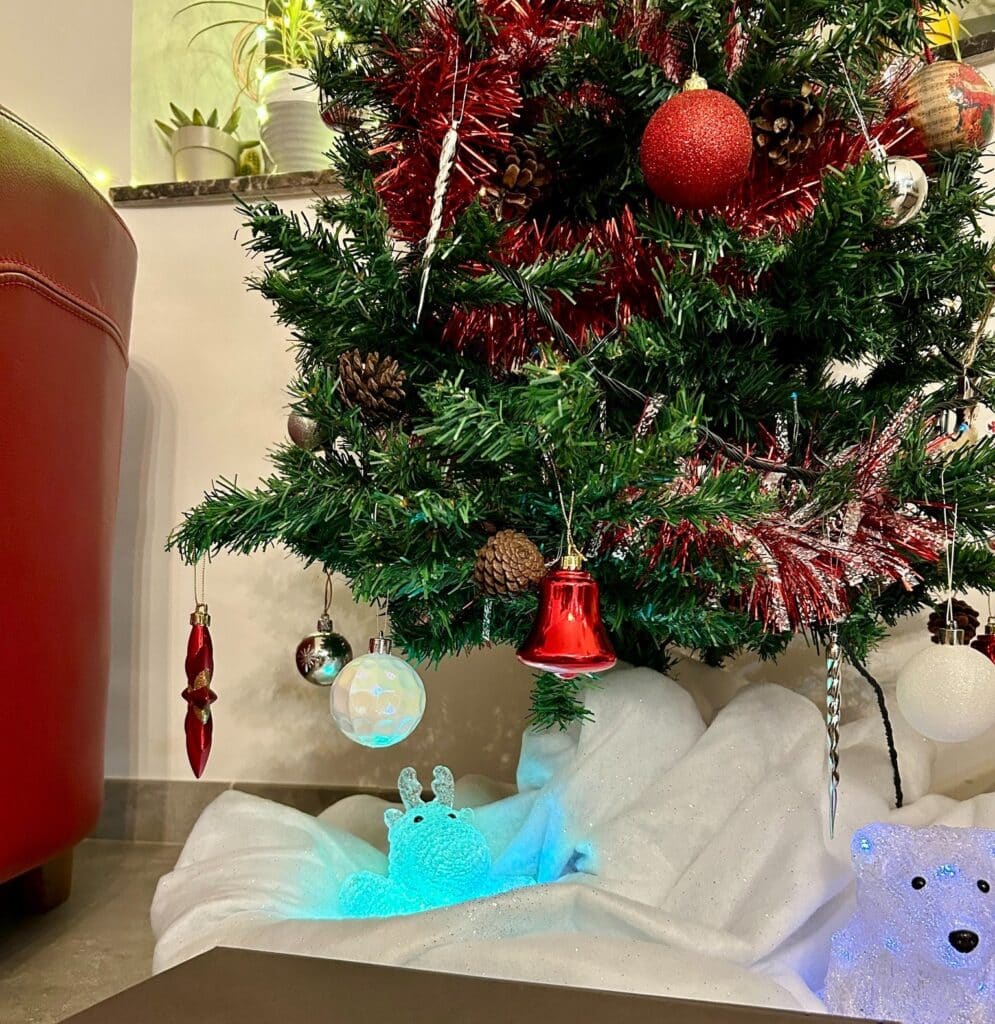 Sapin Noël décoré avec guirlandes rouges et ornements.