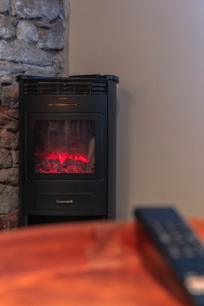 Cheminée électrique moderne devant un mur en pierre.