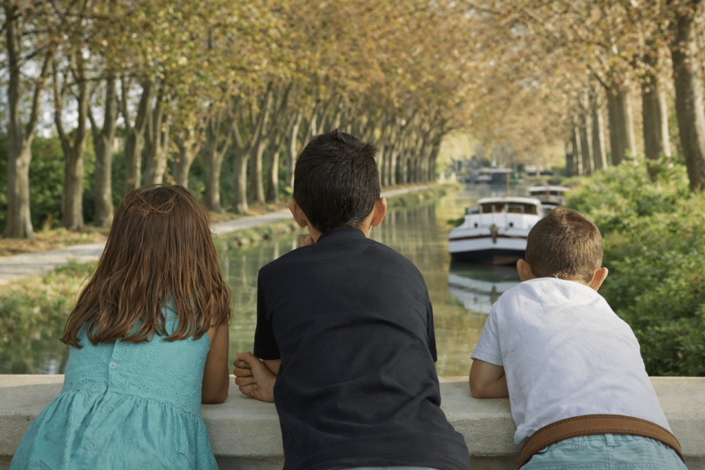 Enfants observant canal avec bateaux en automne.