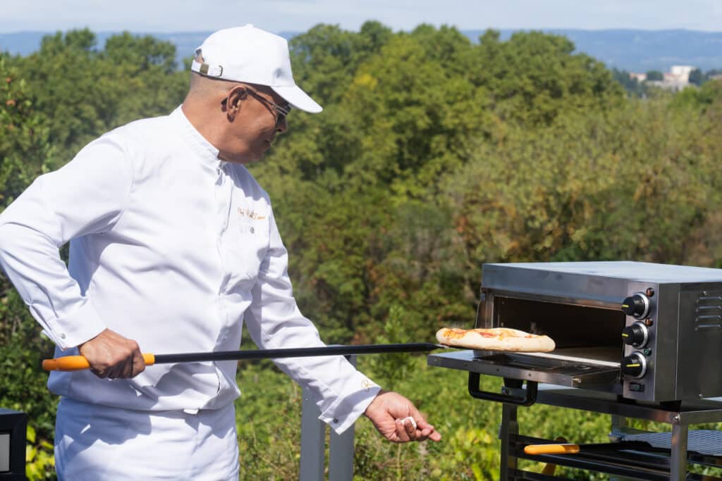 Chef retirant une pizza du four extérieur