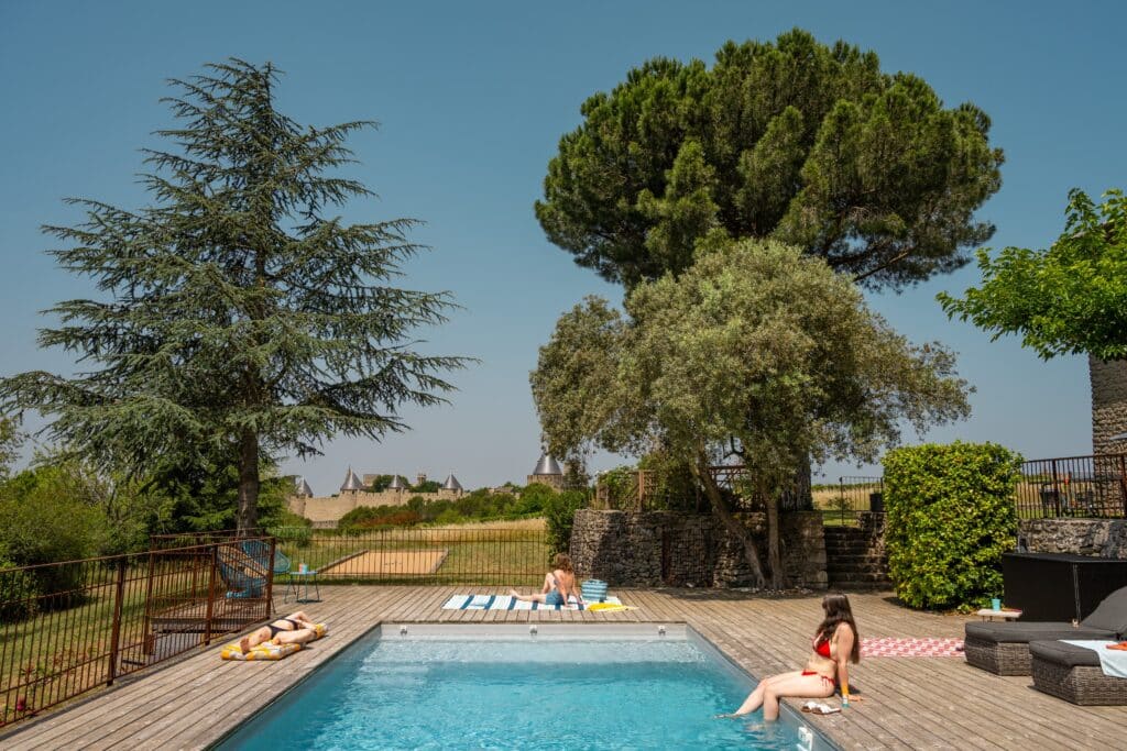 Piscine extérieure avec personnes se détendant au soleil.