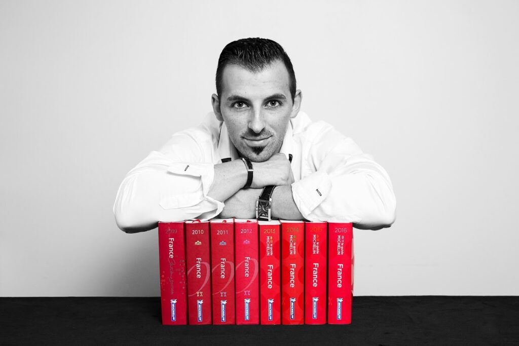 Homme appuyé sur guides Michelin France colorés