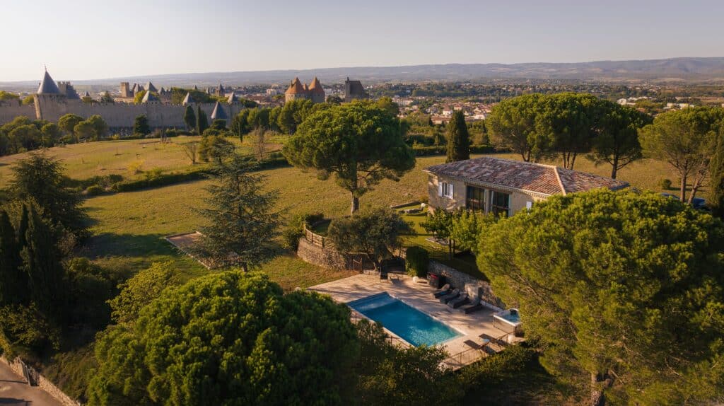 Vue sur château médiéval et villa avec piscine.