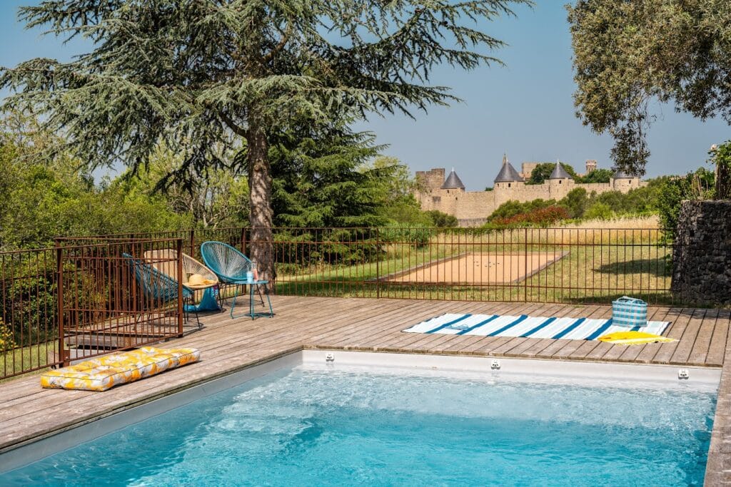 Terrasse avec piscine et vue sur château fort.
