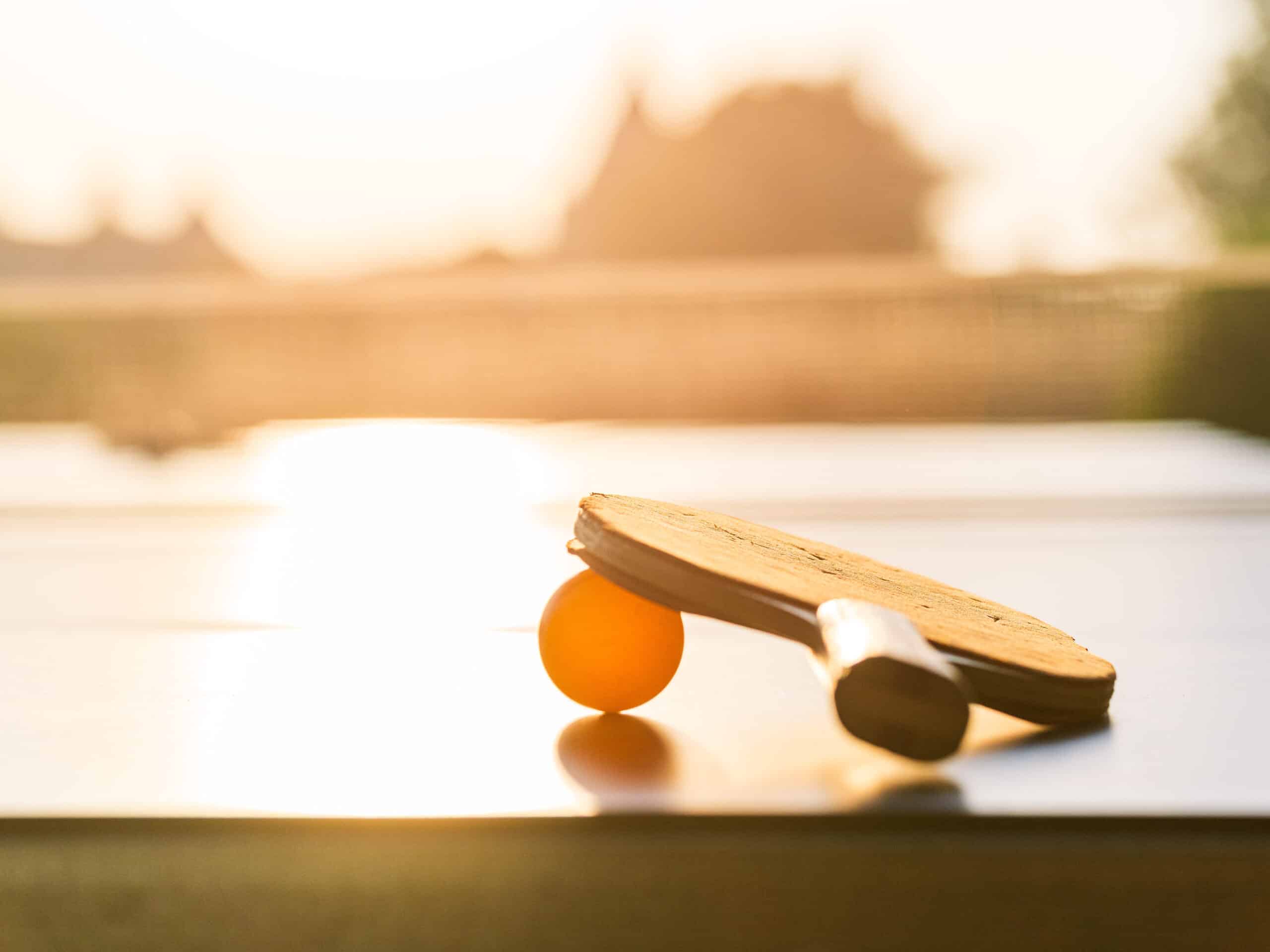 Raquette et balle de ping-pong au coucher du soleil.