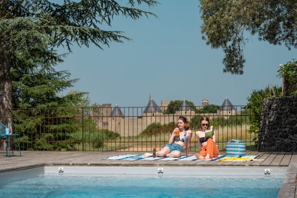 Deux femmes au bord d'une piscine, chateau en arrière-plan.