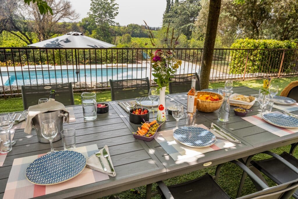 Table de jardin avec piscine et vaisselle colorée.