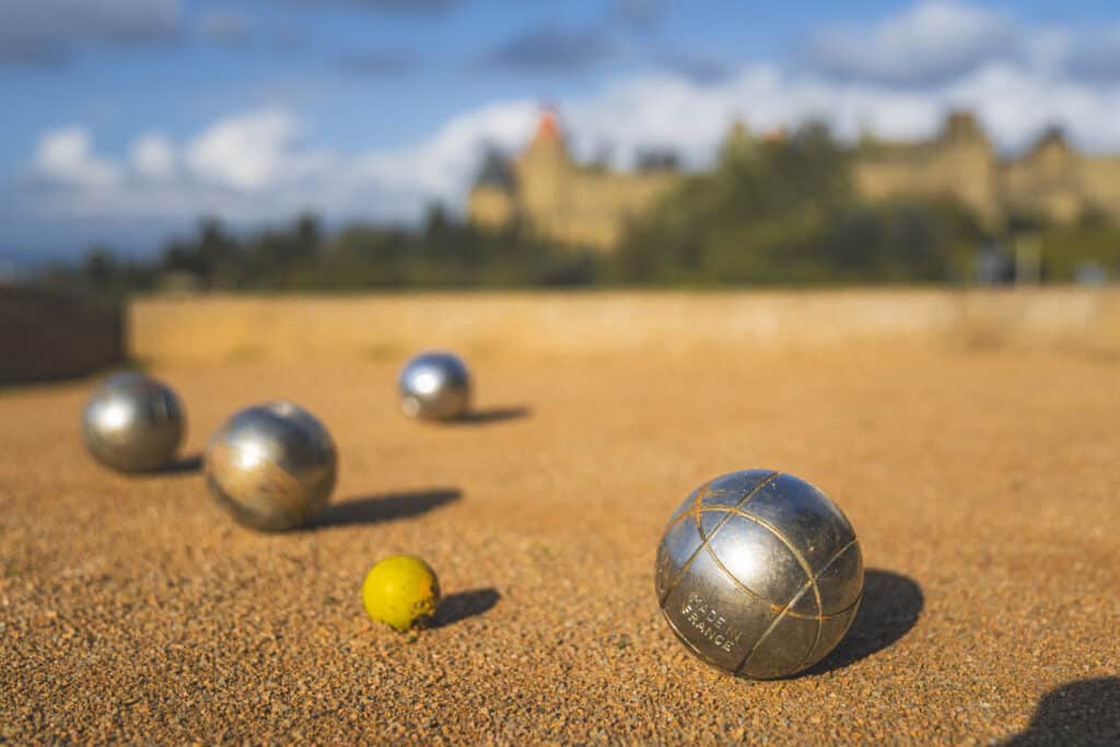 Boules de pétanque sur terrain ensoleillé.