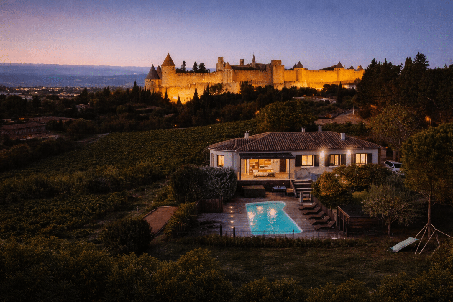 Maison avec vue sur château illuminé au crépuscule.
