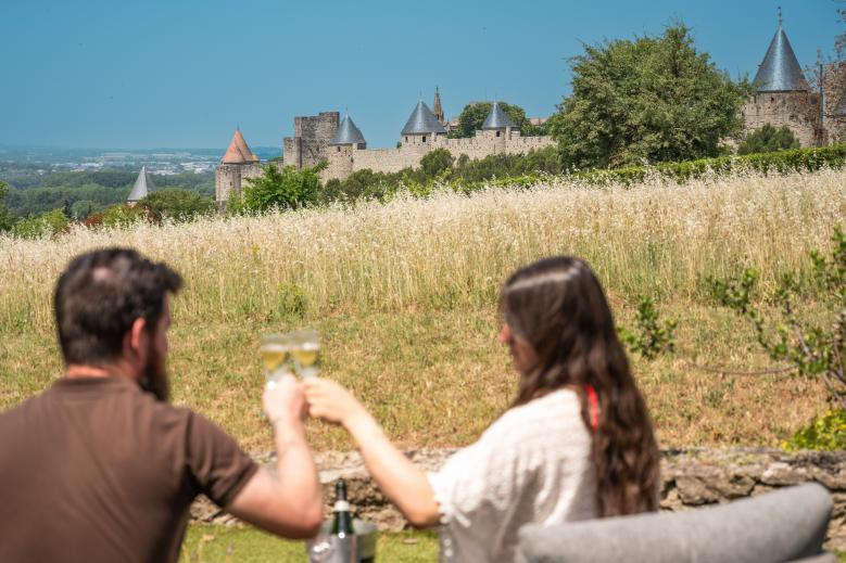 Couple trinquant face à la Cité de Carcassonne depuis le jardin de la villa